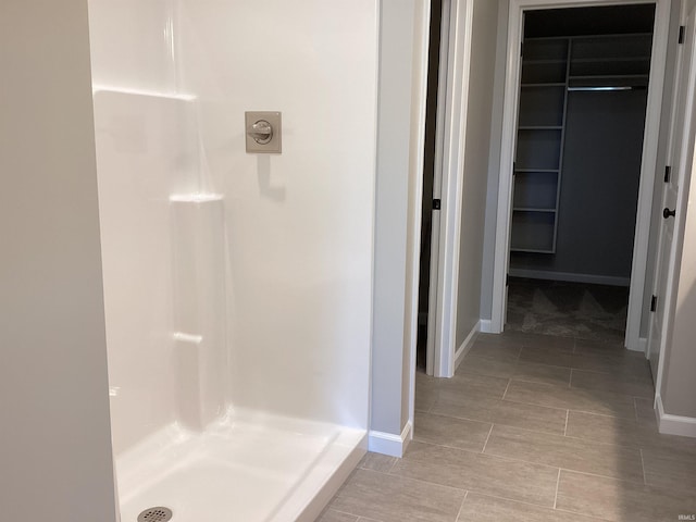 221 Grey Goose Blvd, Decatur, IN 46733 - bathroom featuring a stall shower, baseboards, a walk in closet, and tile patterned floors