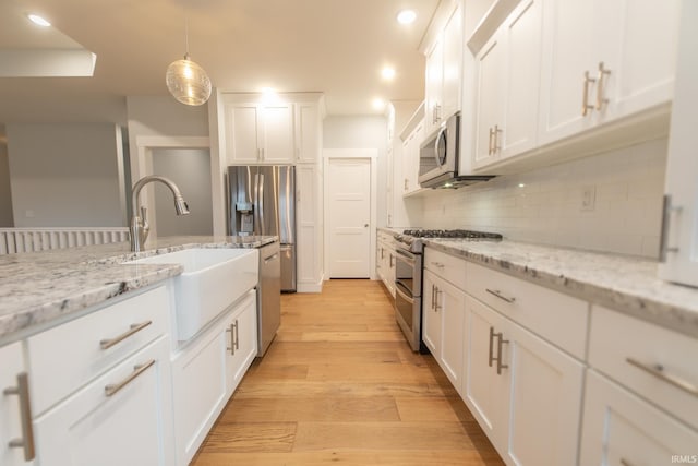 735 E Holland Dr, Bloomington, IN 47401 - kitchen with stainless steel appliances, white cabinetry, decorative backsplash, light wood-style floors, and recessed lighting