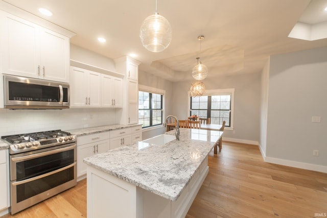 735 E Holland Dr, Bloomington, IN 47401 - kitchen with stainless steel appliances, a sink, baseboards, light wood-style flooring, and white cabinets