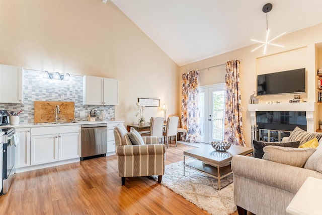 living area featuring high vaulted ceiling, light wood-type flooring, and a tile fireplace
