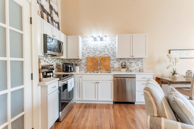 kitchen with appliances with stainless steel finishes, a sink, backsplash, and light countertops