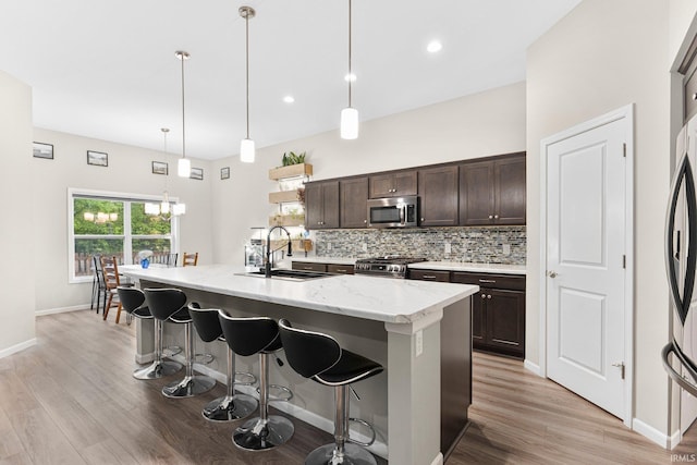 7689 Accio Cv, Fort Wayne, IN 46835 - kitchen featuring appliances with stainless steel finishes, a sink, dark brown cabinets, light wood-style flooring, and a breakfast bar area