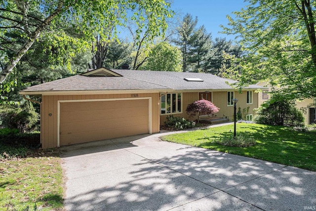 single story home featuring concrete driveway, an attached garage, a front yard, and a shingled roof