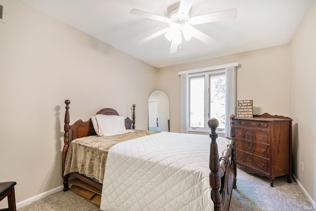 bedroom featuring light carpet, baseboards, ceiling fan, and arched walkways
