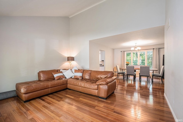 living area with a chandelier, light wood-style flooring, a high ceiling, and baseboards