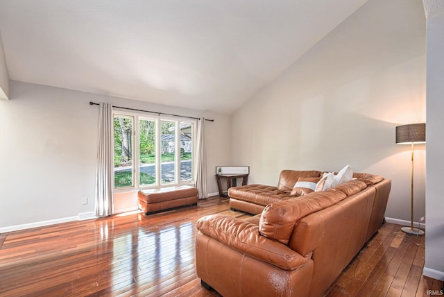 living room featuring hardwood / wood-style flooring, vaulted ceiling, and baseboards