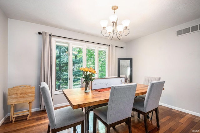 dining room with a chandelier, dark wood-type flooring, and baseboards