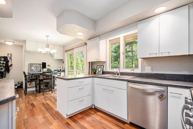 kitchen with stainless steel dishwasher, a sink, dark countertops, a peninsula, and white cabinets