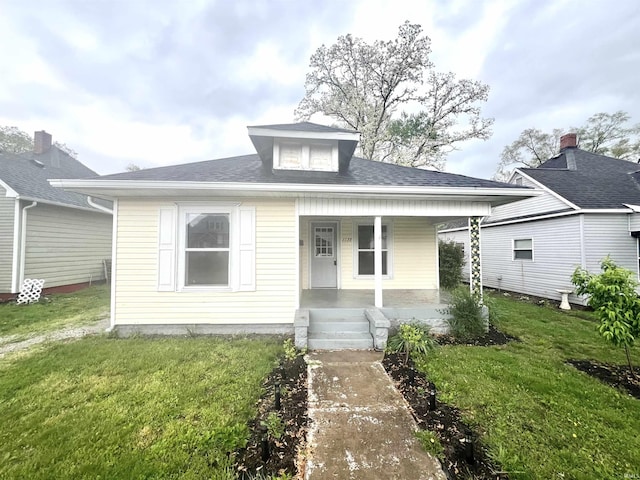 bungalow featuring a porch, a front lawn, and roof with shingles