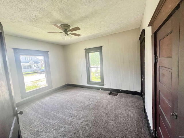 carpeted spare room with baseboards, a textured ceiling, and a ceiling fan
