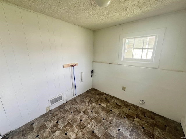 laundry room featuring a textured ceiling and wood walls