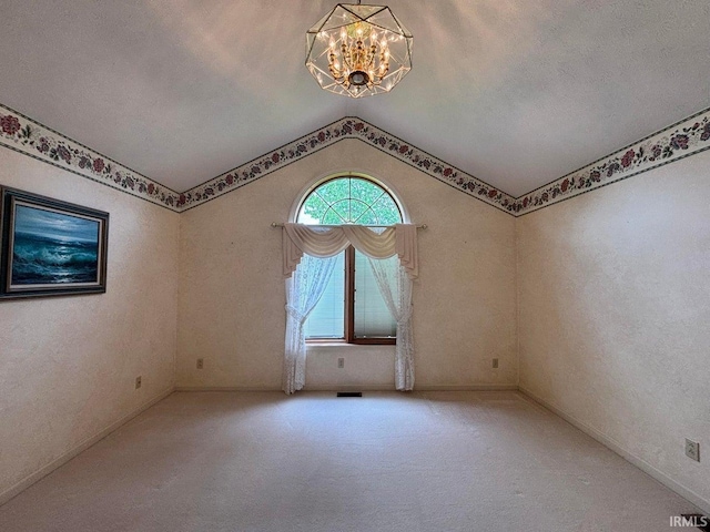 spare room with a chandelier, lofted ceiling, and carpet floors