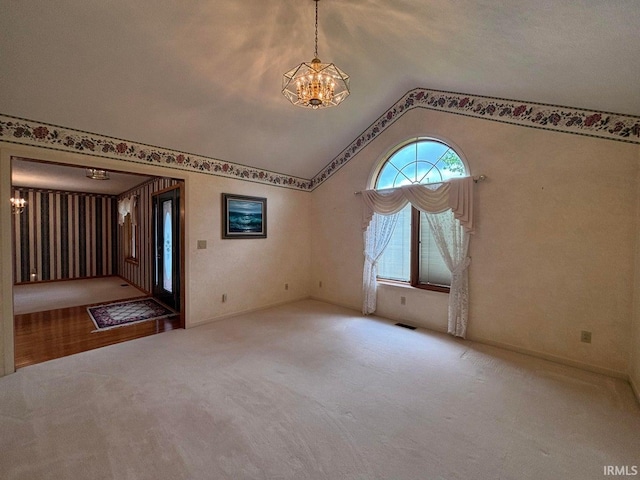 carpeted empty room with a chandelier and vaulted ceiling