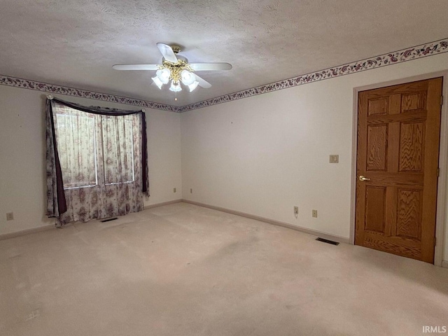 carpeted empty room featuring a ceiling fan, a textured ceiling, and baseboards