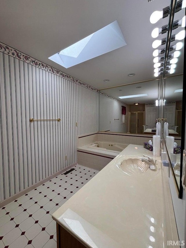 bathroom with a skylight, tile patterned floors, wallpapered walls, vanity, and a tub to relax in