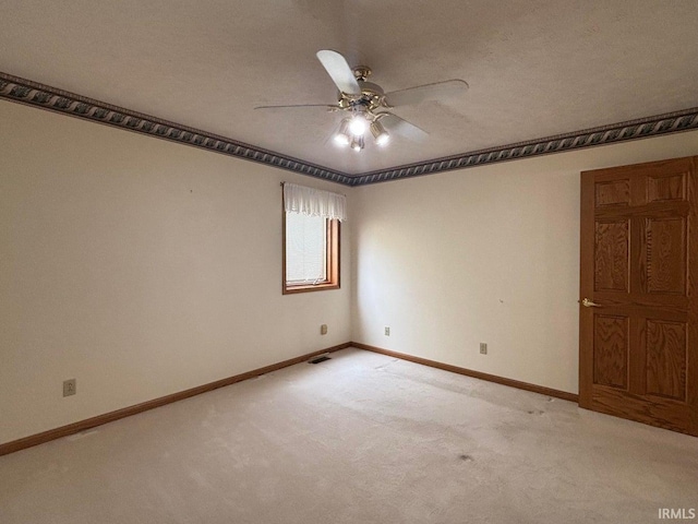empty room featuring ceiling fan, light colored carpet, and baseboards