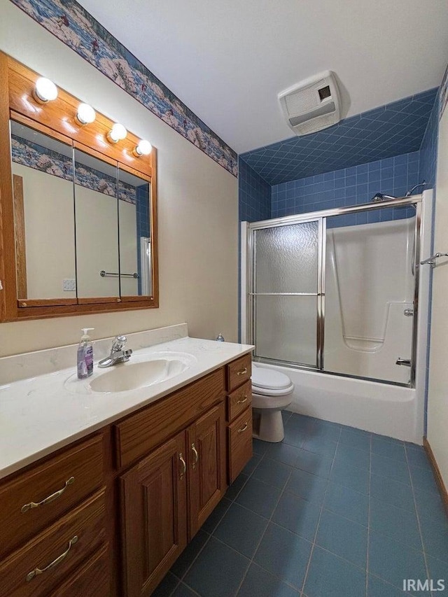 bathroom with tile patterned floors, vanity, toilet, and combined bath / shower with glass door