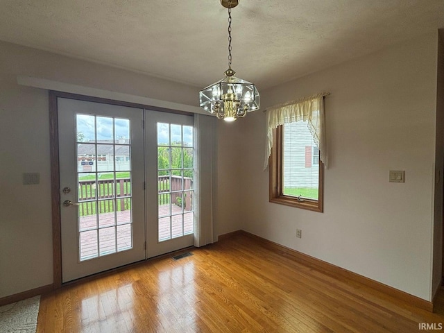 doorway featuring a chandelier, light wood finished floors, and baseboards