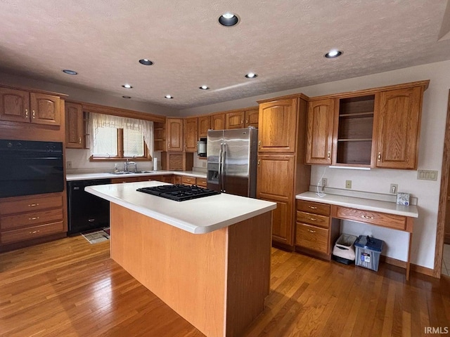 kitchen featuring open shelves, black appliances, a sink, light countertops, and recessed lighting