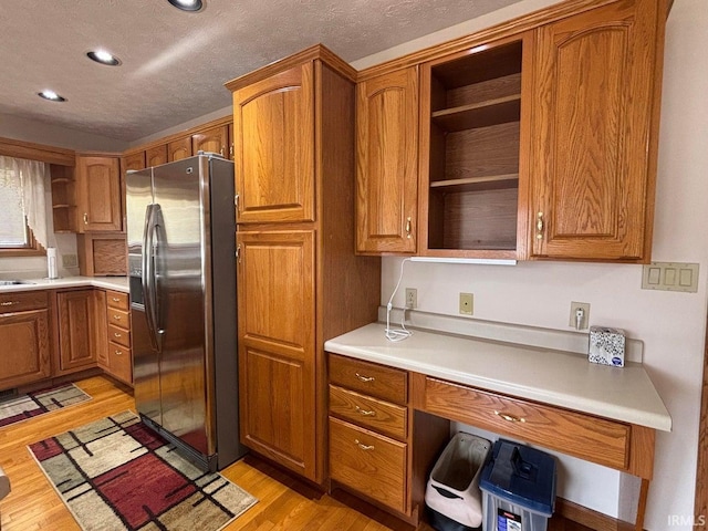 kitchen with stainless steel refrigerator with ice dispenser, open shelves, brown cabinets, recessed lighting, and a textured ceiling
