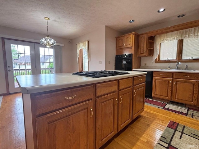 kitchen featuring black appliances, a sink, light wood finished floors, light countertops, and recessed lighting