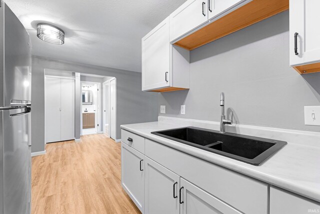 2937 Westbrook Dr Unit A-314, Fort Wayne, IN 46805 - kitchen with freestanding refrigerator, a sink, light wood-style flooring, light countertops, and white cabinetry
