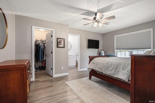 bedroom with light wood-style flooring, baseboards, a spacious closet, a ceiling fan, and a closet