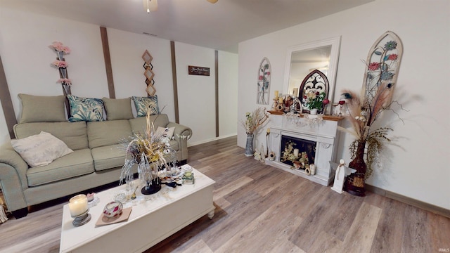 living room featuring wood finished floors, ceiling fan, and a fireplace
