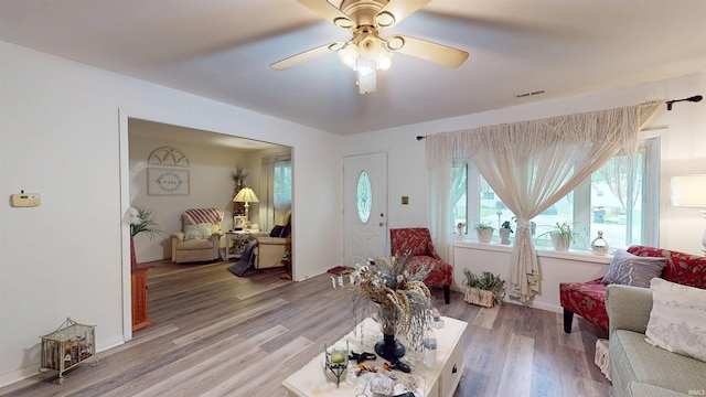 living area featuring ceiling fan, light wood-type flooring, and baseboards