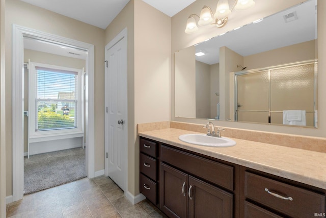 bathroom featuring vanity, a stall shower, baseboards, and tile patterned flooring