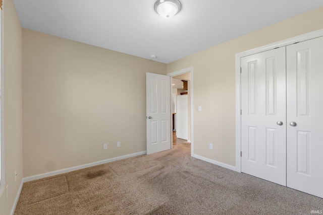 unfurnished bedroom featuring carpet floors, baseboards, a closet, and freestanding refrigerator