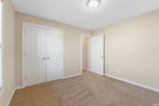 unfurnished bedroom with carpet, a closet, and baseboards