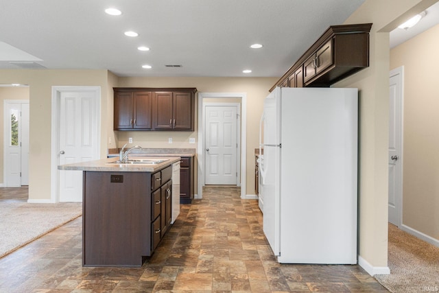 kitchen with freestanding refrigerator, dark brown cabinetry, baseboards, light countertops, and a center island with sink