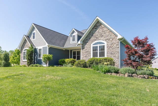 view of front of house with stone siding, a front yard, and a shingled roof