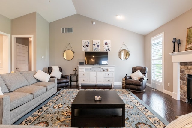 living area featuring wood finished floors, a stone fireplace, baseboards, and high vaulted ceiling