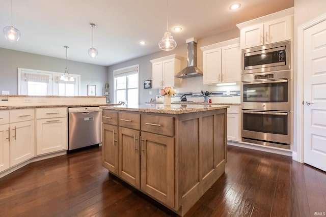 kitchen with stainless steel appliances, wall chimney range hood, dark wood-type flooring, recessed lighting, and a kitchen island