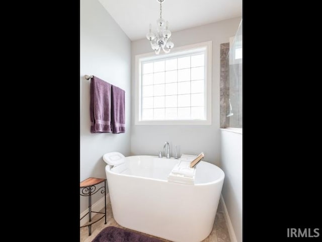 full bathroom with a chandelier, a freestanding tub, and baseboards