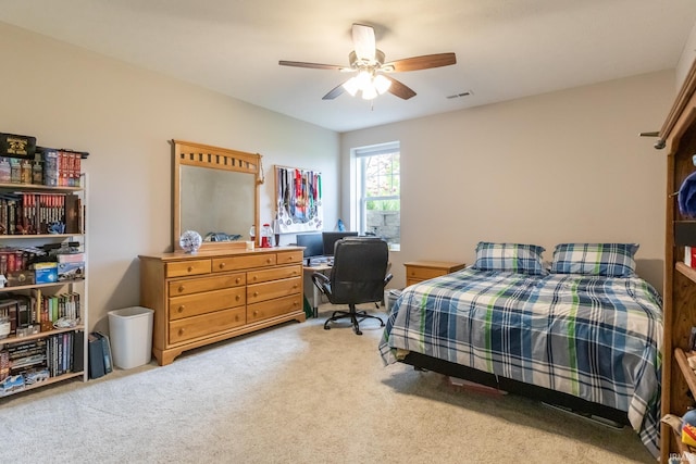 bedroom with a desk, light carpet, and ceiling fan