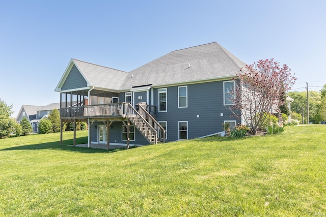 rear view of house with a sunroom, a wooden deck, a lawn, stairway, and roof with shingles