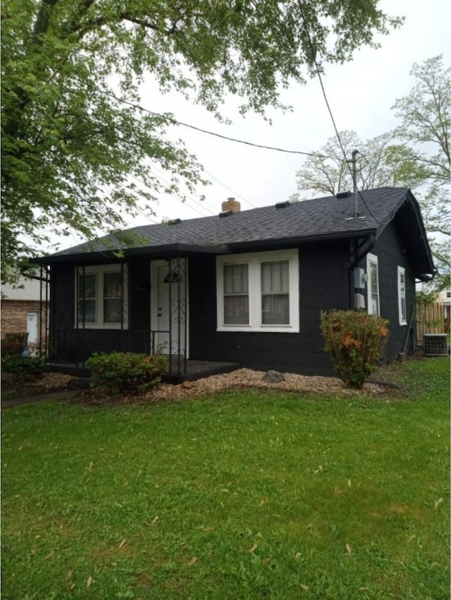 view of front of property with a front lawn, cooling unit, and a shingled roof