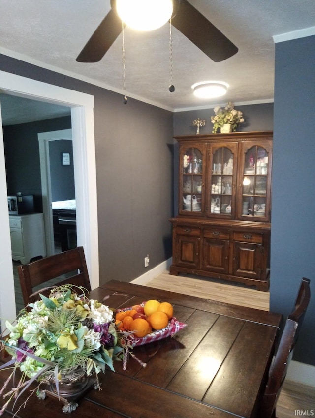 dining space featuring ceiling fan, light wood-style flooring, crown molding, and baseboards