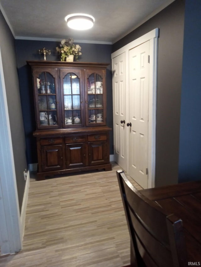 entryway featuring light wood-style floors, ornamental molding, and baseboards