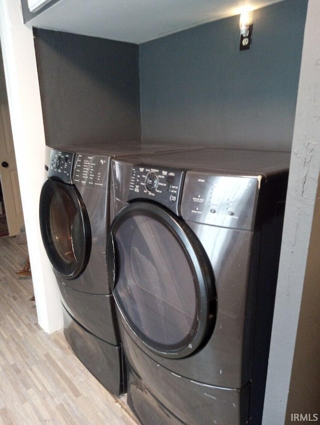 laundry area with washer and dryer and wood finished floors