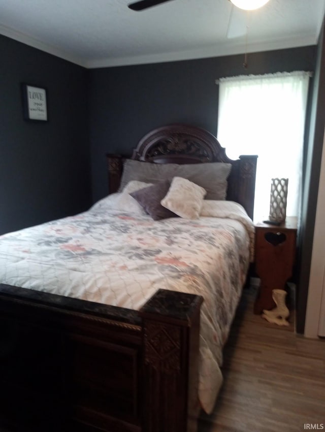 bedroom with wood finished floors, crown molding, and ceiling fan