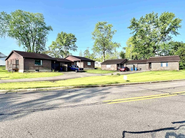 single story home featuring brick siding, a front yard, and asphalt driveway