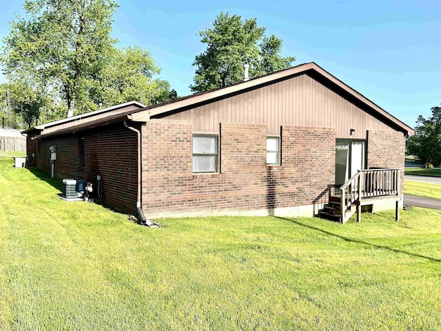 view of property exterior featuring brick siding, cooling unit, and a yard