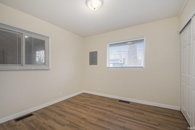 unfurnished bedroom featuring a closet, baseboards, wood finished floors, and electric panel