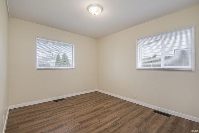 empty room with dark wood-style flooring and baseboards