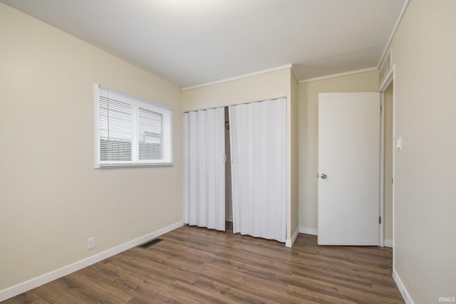 unfurnished bedroom with dark wood finished floors, baseboards, and a closet