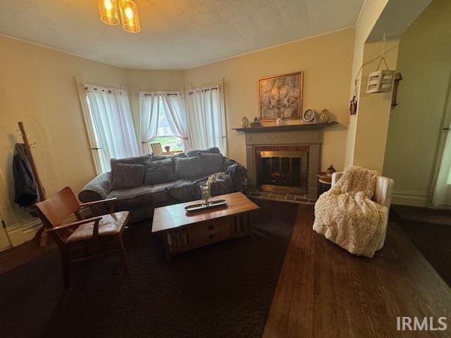 living room featuring a brick fireplace, wood finished floors, and a chandelier